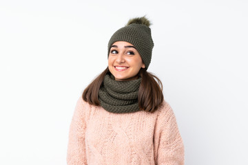 Young girl with winter hat over isolated white background laughing and looking up