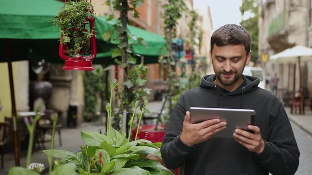 Urban man using tablet computer outside app on 5g wireless device. Casual young professional male in late 20s. Hand touching digital screen pad pc