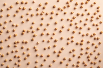 Separated small raw grains of chick pea beans chaotically scattered on light tan, creamy background. Dried uncooked Kabuli chickpea (garbanzo bean). Cicer arietinum seeds. Texture, Top view. 