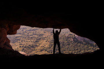 MOUNTAINEER CLINGING TO THE ROOF OF A CAVE ATOP A MOUNTAIN