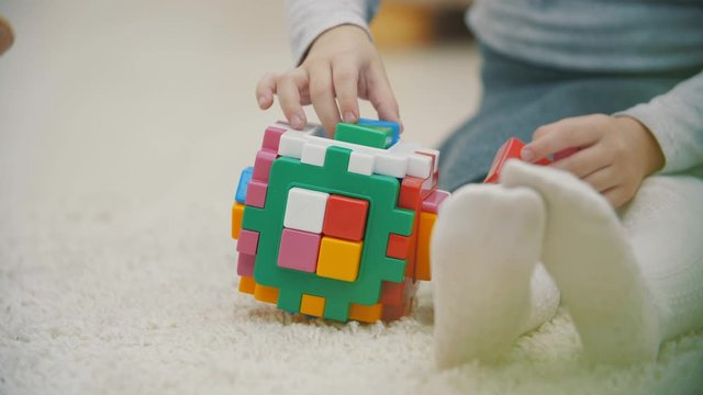 4k slowmotion video of baby playing with colorful pyramid on the carpet.
