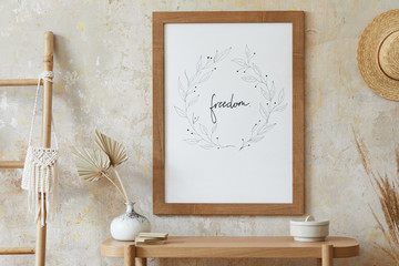 Beige boho interior of living room with mock up poster frame, elegant accessories, dried flowers in vase, wooden console and hanging rattan hut in stylish home decor. © FollowTheFlow