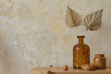 Wabi sabi interior of living room with wooden console, paper flowers in vase, nuts and copy space. Minimalistic concept.