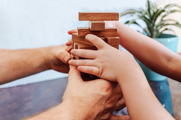Father and child playing game tumble tower from wooden block