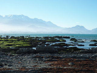 Scenic shot of a rocky seashore with a foggy mountain on the background