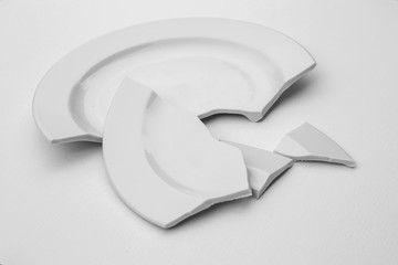 fragments of a broken plate on a light background, black and white photo. The concept of breaking...