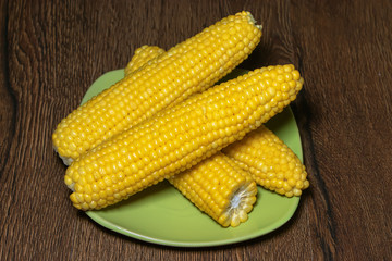 Boiled corn on a plate on wooden background