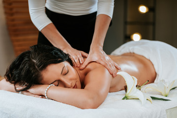 Masseur doing massage on beautiful young woman body in the spa salon. Professional masseur and clien concept.