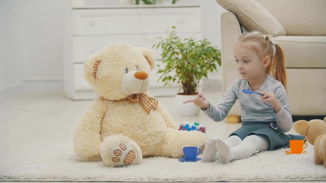 4k slowmotion video of cute little girl feeding teddy bear.