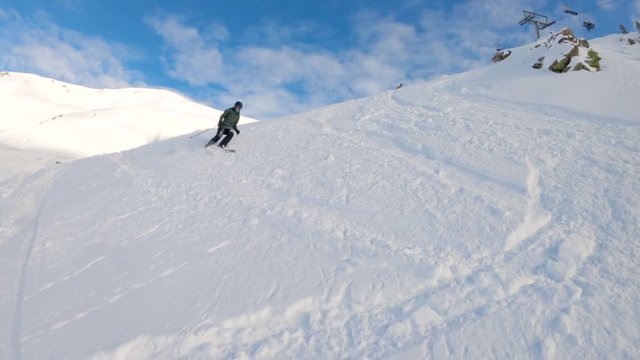 Slow motion of a female skier descends a ski slope, falls down and smiles at the camera. It's a sunny winter day in spanish Pyrenees.