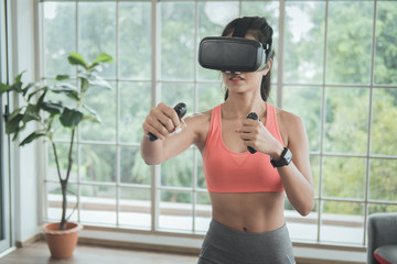 Young woman wearing VR headset doing working out interacting with 3d simulation at home.