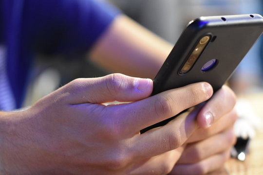 Smartphone consultado relajadamente por un joven en luminoso entorno laboral tecnol&oacute;gico