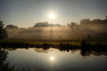 Obraz premium Early morning mist over the meadows on the River Wey in Godalming, Surrey, on a cold autumn morning.