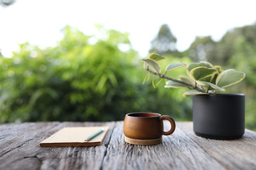 Wooden coffee cup with notebook and Hoya kerrii in black pot