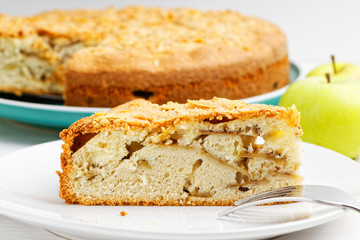 Closeup piece of apple pie with almond petals  on white wooden table. Shallow focus.