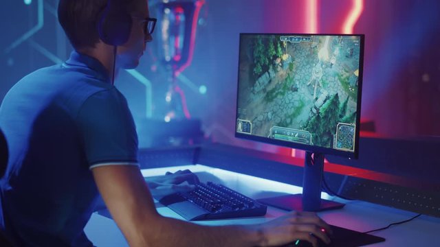Professional eSports Gamer Plays RPG MOBA Mock-up Video Game with Super Action and Fun Special Effects on His Personal Computer, Talks to Teammates using Headset. Cyber Gaming Stylish Retro Neon Room