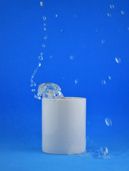 As main shot, white porcelain cup on blue background, splash