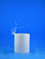 Obraz na płótnie Canvas As main shot, white porcelain cup on blue background, splash