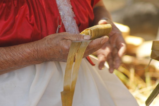 indigenous woman's hands wrapping tamale in corn husk mexican corundas