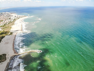 Green and blue colors of Black Sea captured from the sky. Light beaches with white stone docks hitted by big waves.