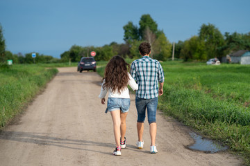 Brother and sister walking together. Happy couple walking along the road. Girl and guy walking...