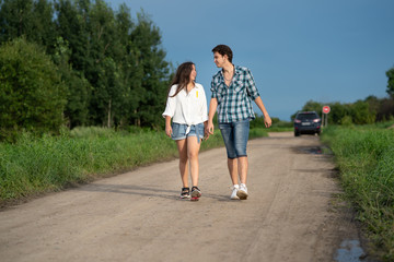 Obraz premium Brother and sister walking together. Happy couple walking along the road. Girl and guy walking countryside. Healthy lifestyle concept.