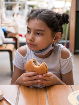 Child Eating A Burger With Mask