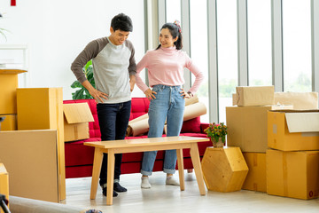 young Asian couple loers move the cardboard boxes to new family house