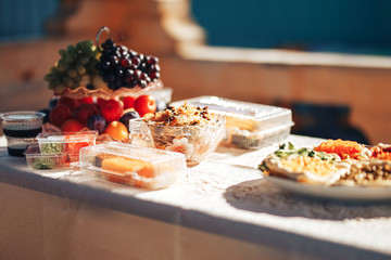 Long table covered with a tablecloth on which there is a lot of food, food in plates