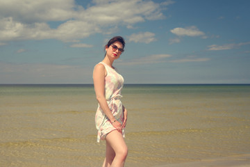 Fototapeta na wymiar young happy girl in summer dress by the sea