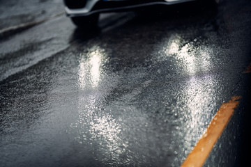 Car on wet and slippery asfalt. Close up on tires and the road. Rain and wet driving conditions. 