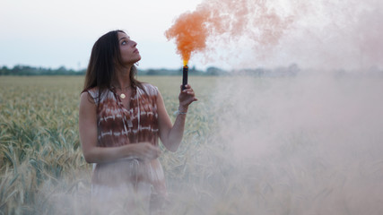 Closeup shot of a young brunette posing with a colorful bomb in the field
