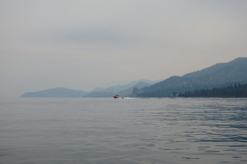Red Motorboat and Wakeboarder on Lake Tahoe Surrounded by Smokey Skies Over Lake Tahoe and Surrounding Western Sierras from Wildfires of August 2020