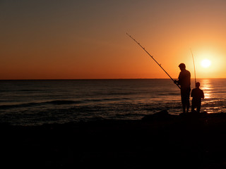 silhouette of fisherman by the ocean in sunrise, A fisherman in sunset at the coast
