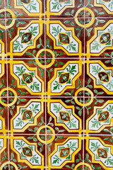Vertical photo of a vintage tiles with geometric and floral borders in vivid warm colo