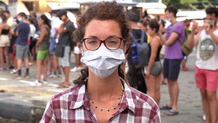 white girl with mask with crowd of people behind her during covid-19 Coronavirus pandemic - social distance 1 meter - Powered by Adobe