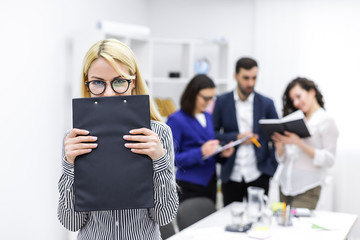 Confident young businesswoman standing with folded arms.