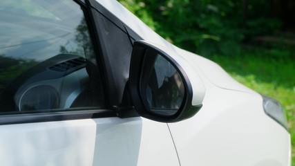 Fold the white car side mirror. Close up