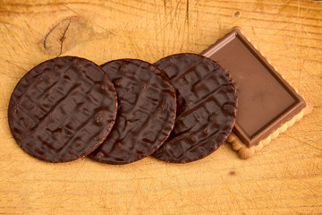 Tabla de madera con varias galletas de chocolate cuadradas y redondas