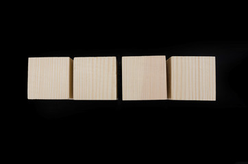 four blank wooden cubes on a black background. View from above.