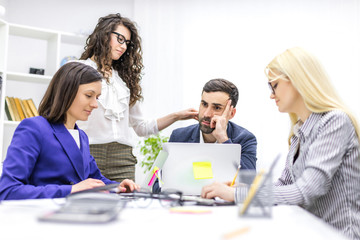 Obraz premium Photo of young beautiful woman gesturing and discussing something while her coworkers listening to her sitting at the office table.