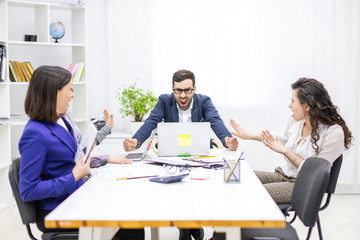 Photo of manager discussing something with his coworkers listening to him sitting at the office table.