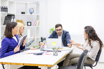Photo of manager discussing something with his coworkers listening to him sitting at the office table.
