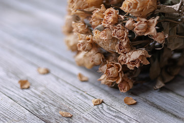 Bunch of dried roses on wooden table, nostalgic memories of the past