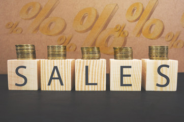 SALE word on wooden cubes, cubes stand on a black surface, in the background - a percent sign. Business and finance concept