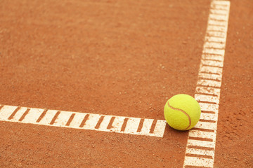 Light green tennis ball on clay court, space for text