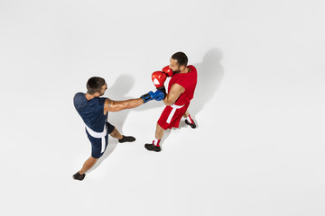 Plakat Two professional boxers boxing isolated on white studio background, action, top view. Couple of fit muscular caucasian athletes fighting. Sport, competition, excitement and human emotions concept.
