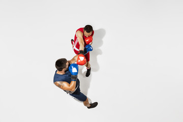 Fototapeta na wymiar Two professional boxers boxing isolated on white studio background, action, top view. Couple of fit muscular caucasian athletes fighting. Sport, competition, excitement and human emotions concept.