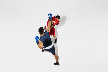 Fototapeta na wymiar Two professional boxers boxing isolated on white studio background, action, top view. Couple of fit muscular caucasian athletes fighting. Sport, competition, excitement and human emotions concept.