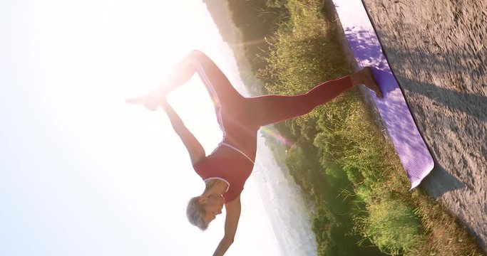 Camera roll 360 An adult woman yoga master does a pose Hip flexors and stands at sunrise